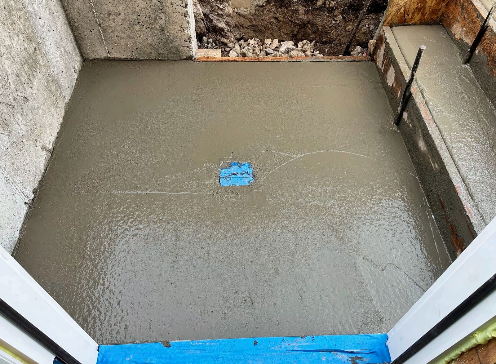 Freshly poured concrete landing at a new basement doorway