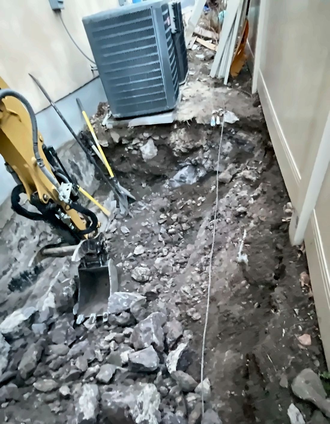 Mini excavator clearing a narrow Utah side yard for a basement entry