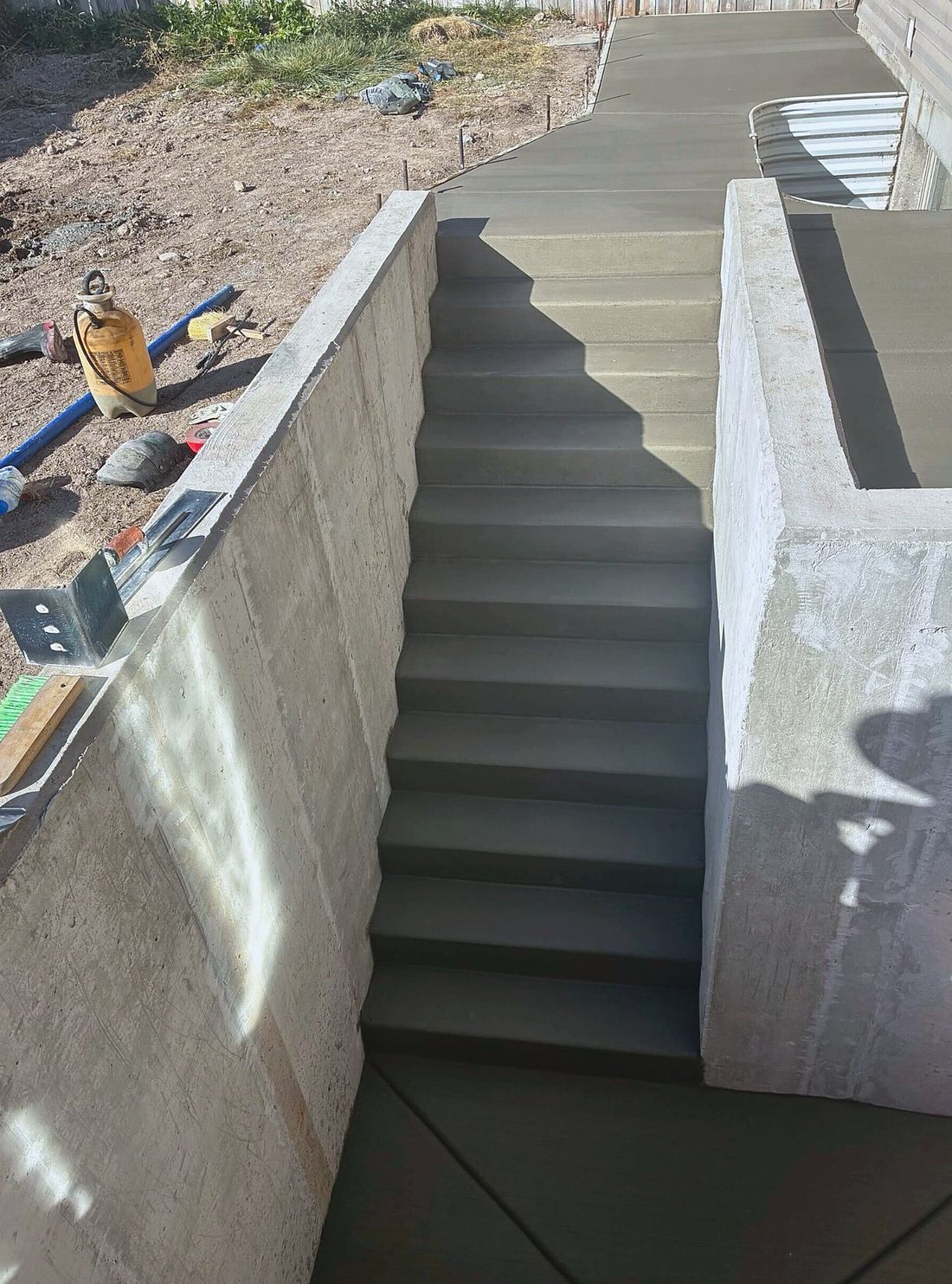 Completed below-grade concrete walkout stairwell with steps and walkway