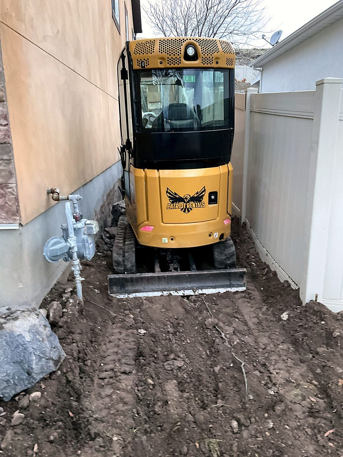 Compact excavator in a narrow Utah side yard